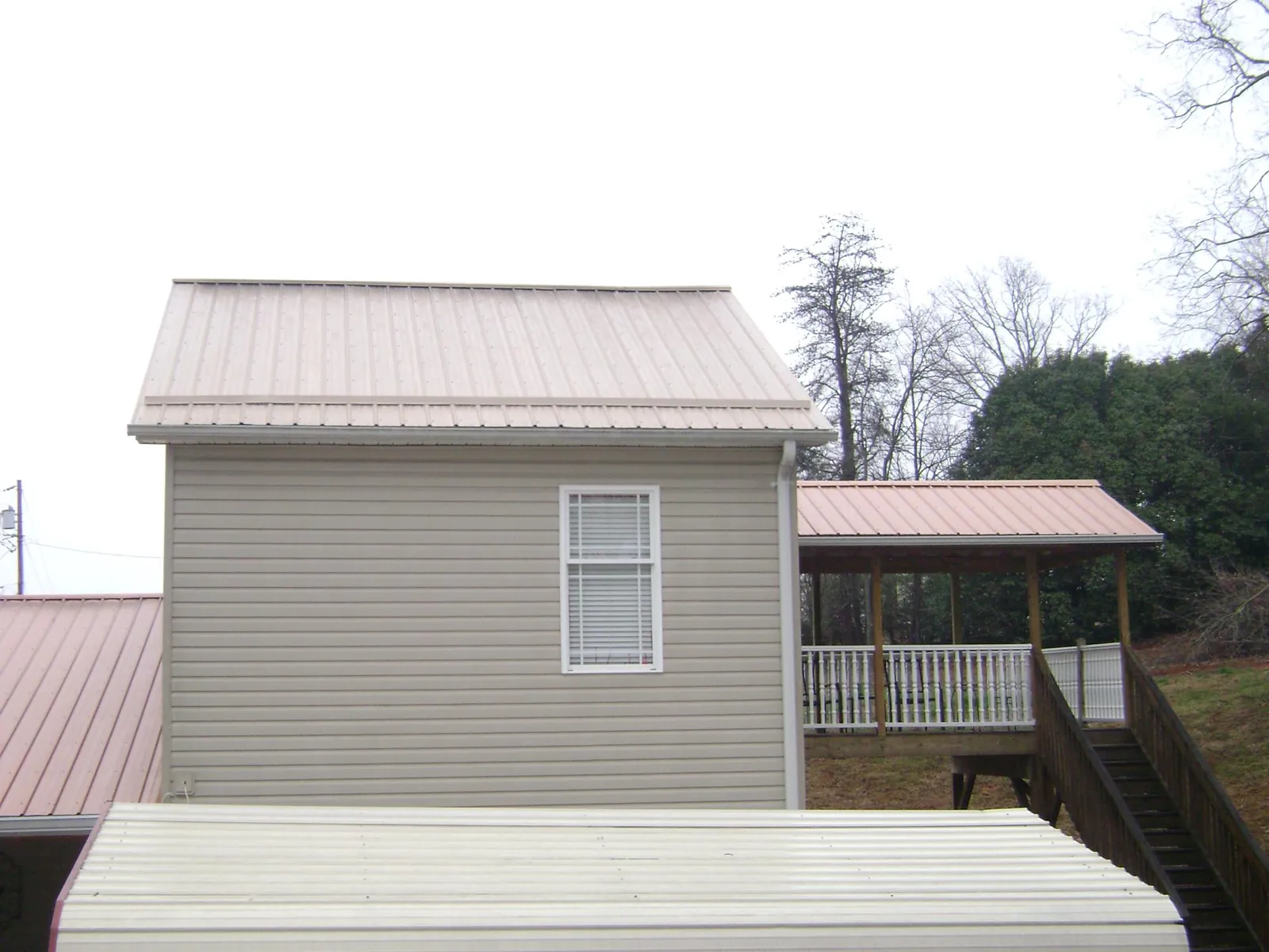 Tan metal roofs on a two story addition and attached porch, from a Roof Replacement job in Grand Canyon