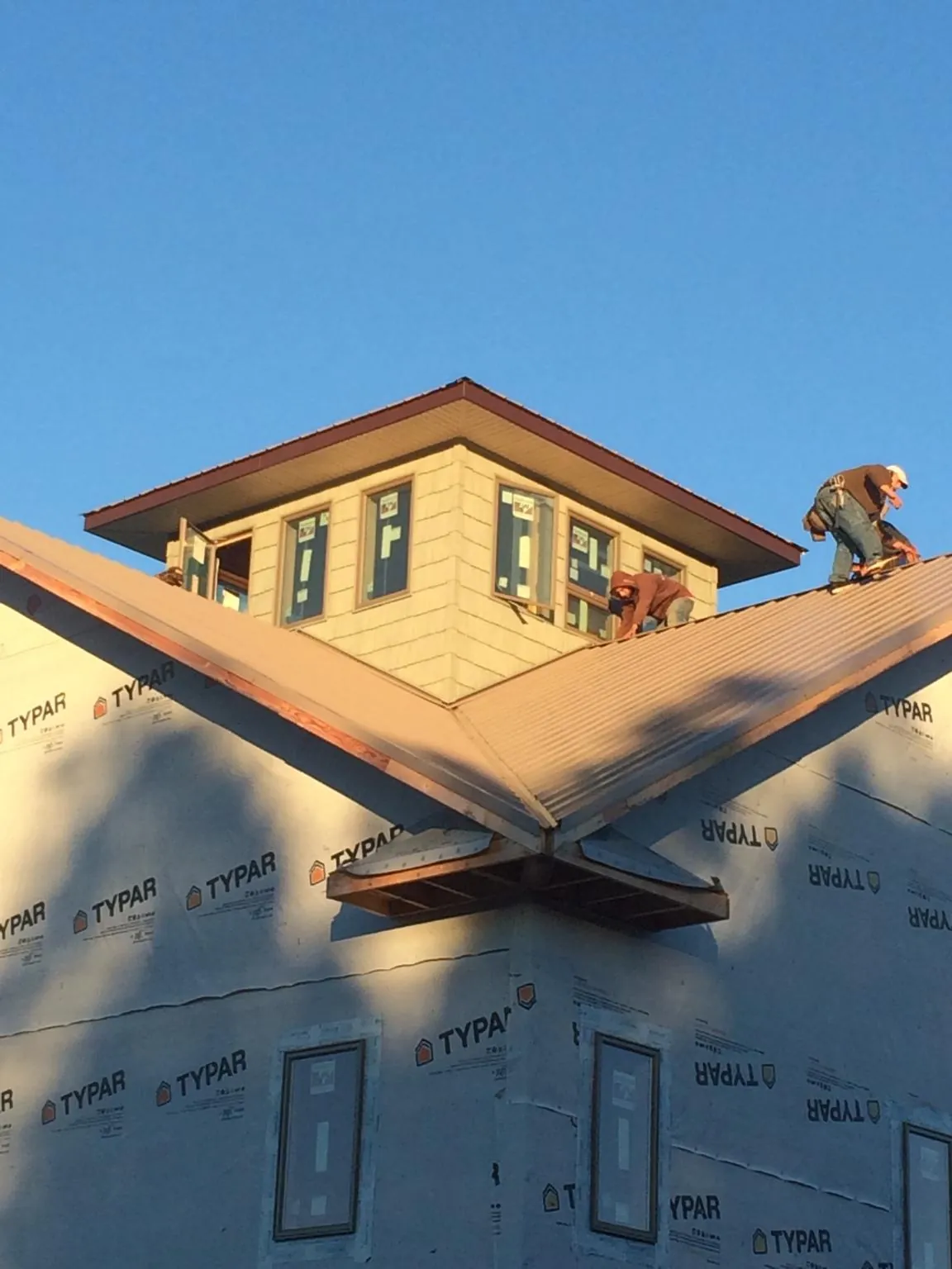 Roofers working around a rooftop cupola on a new metal roof at sunset — Roof Waterproofing in Grand Canyon by Roofing Brothers